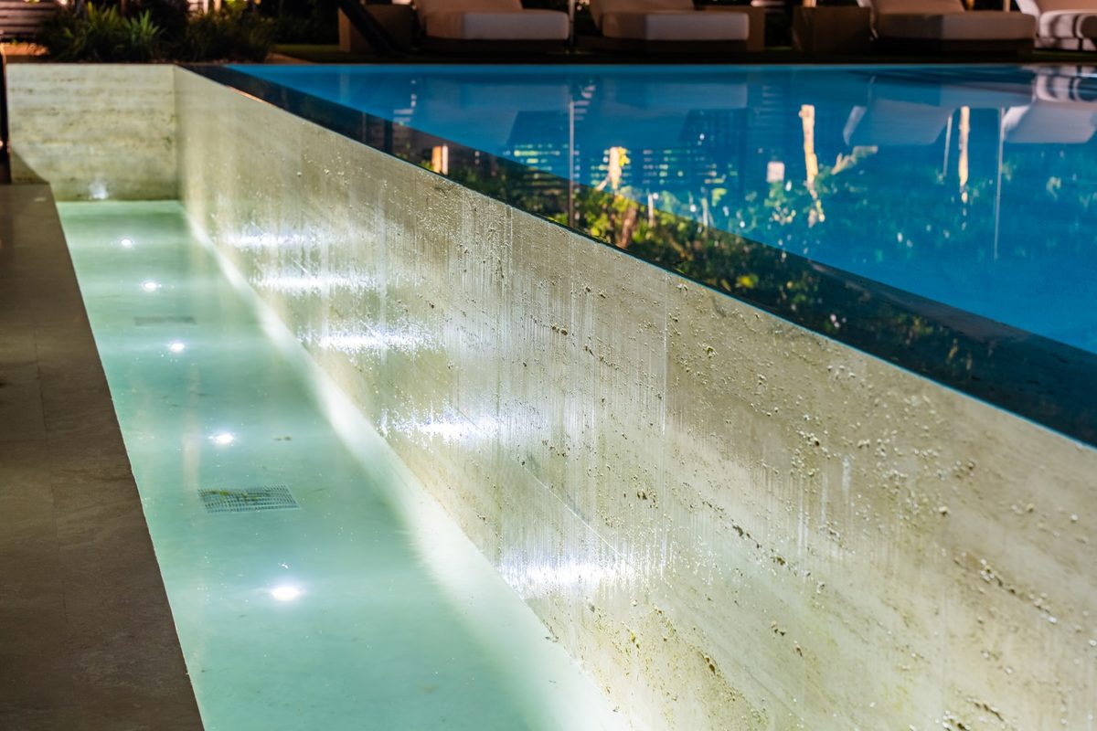 Lit travertine pool wall at night