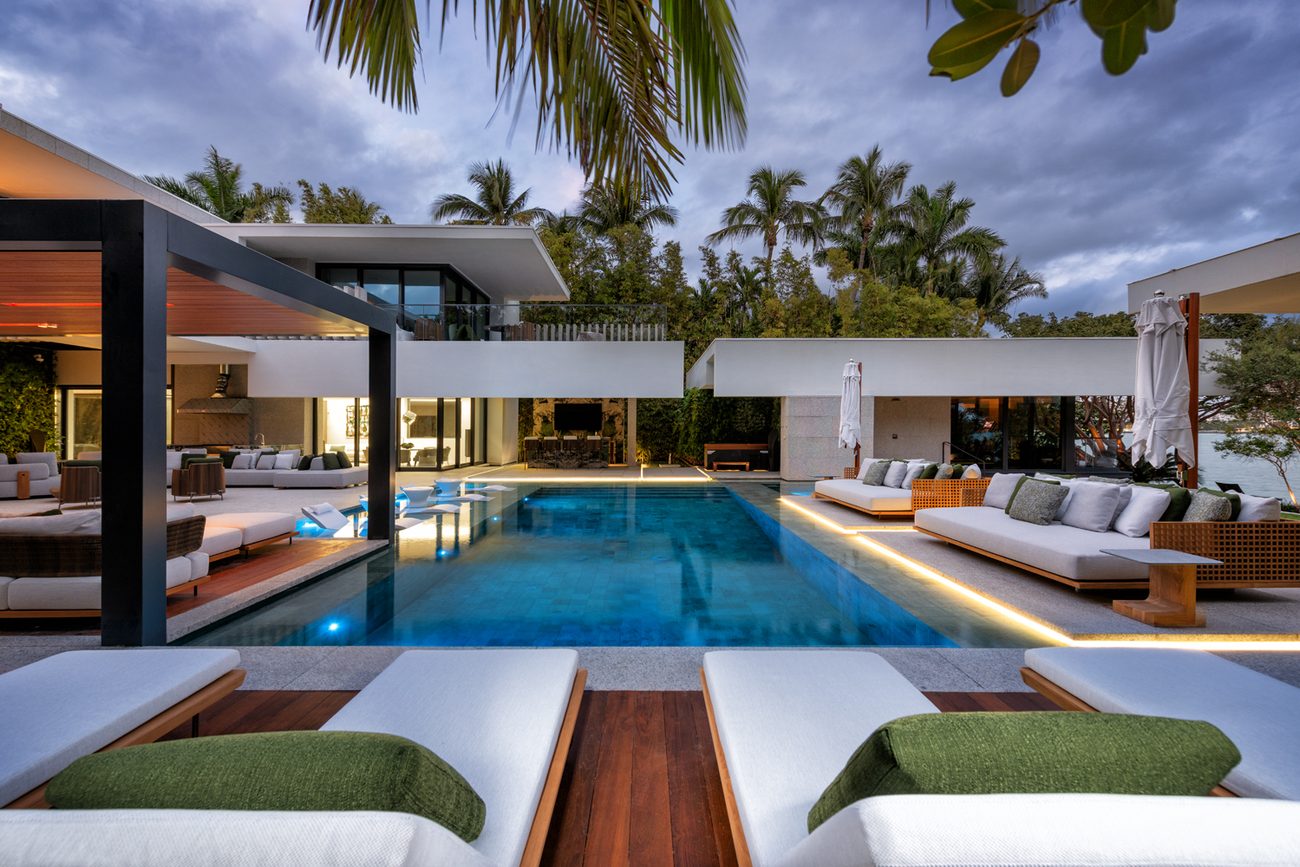 Renovated pool and loungers at dusk with the home lit behind