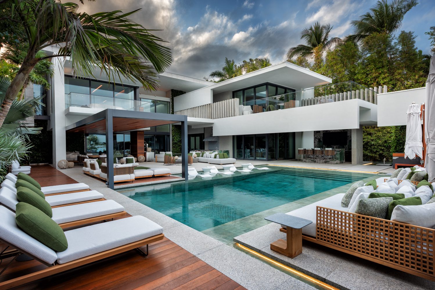 Renovated pool with built-in daybeds and wood decking at a waterfront home on Star Island, Miami Beach