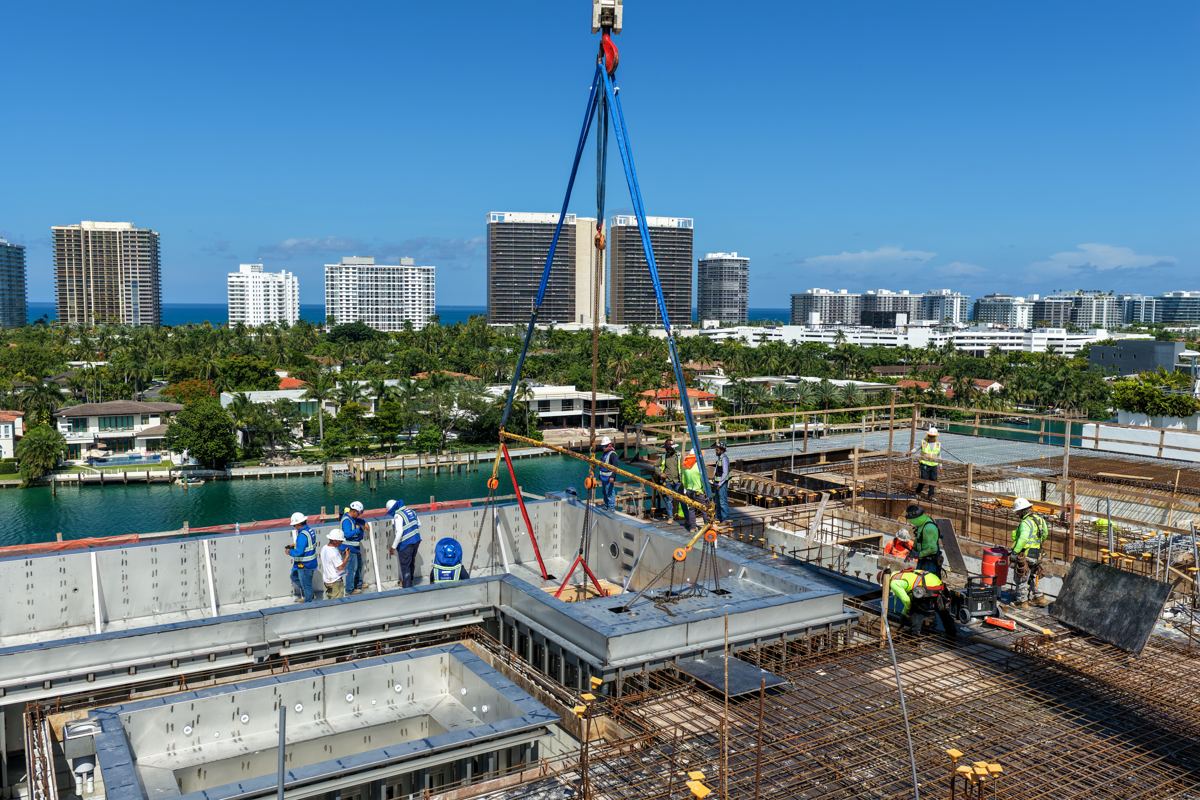 Crane lowering a pool section with the ocean skyline behind
