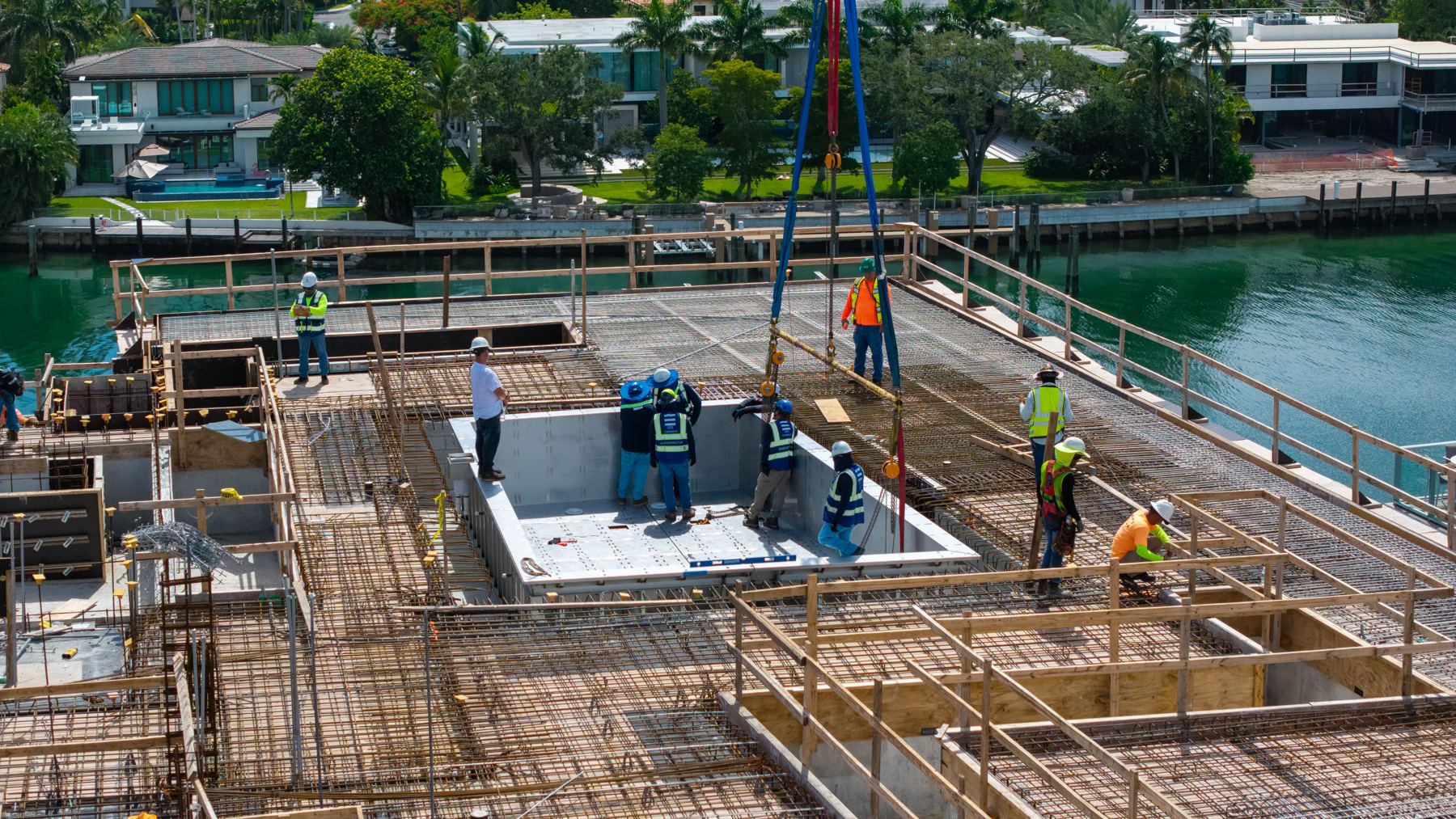 CPS crew aligning a stainless steel pool section on a waterfront rooftop deck