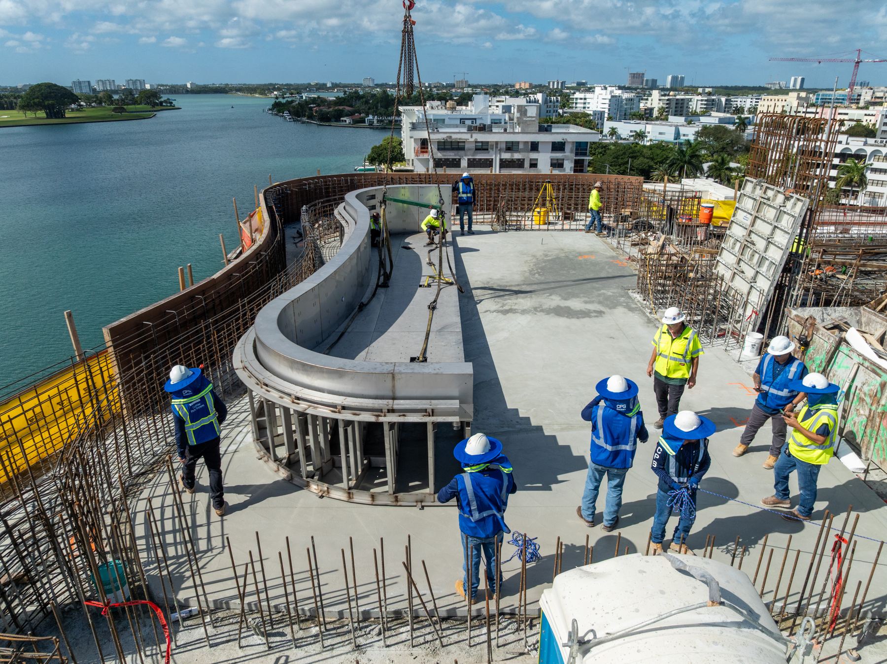 CPS crew setting a curved stainless steel pool shell on a waterfront rooftop in Bay Harbor Islands